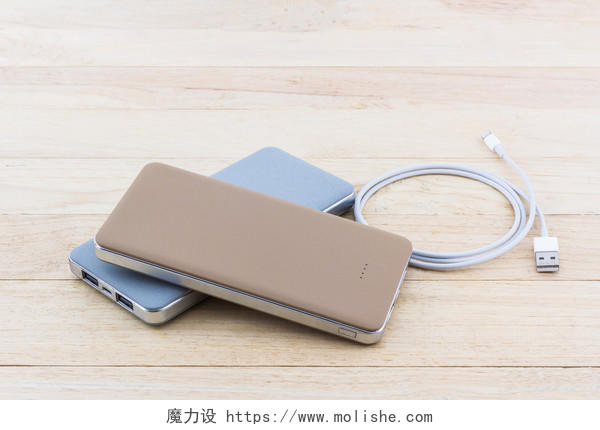 褐色木质桌面上电力银行智能手机和USB电缆
